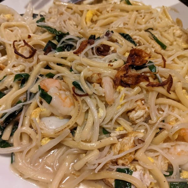 Close-up of Shiok Singapore Kitchen's Hokkien Mee, featuring thick and thin noodles, shrimp, and fried shallots.